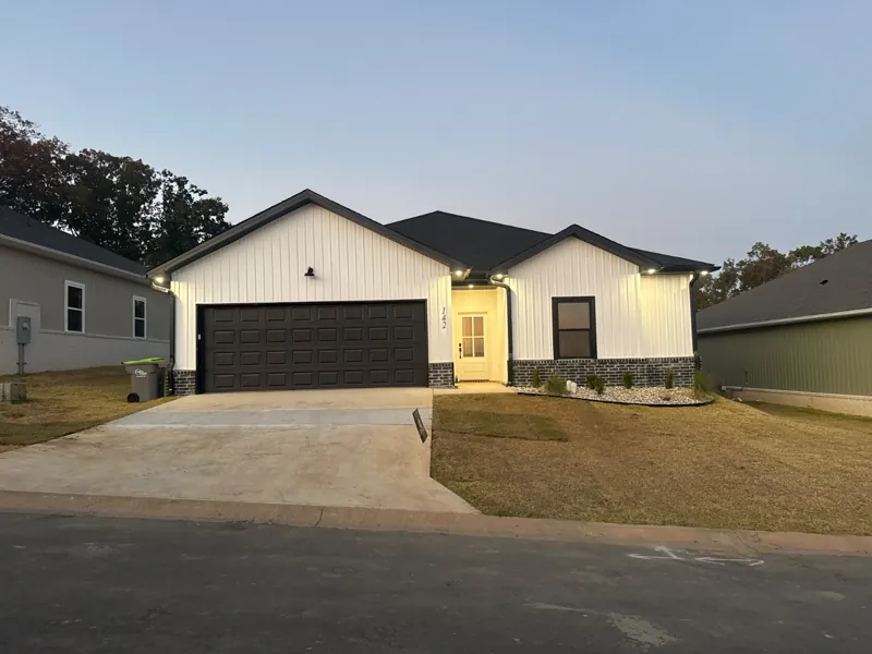 A white home with a dark garage door on Everest Street at dusk